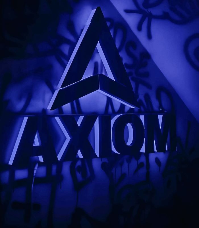 Podświetlane logo AxiomLab z liter drukowanych z PLA+, światło niebieskie odbite od ściany
