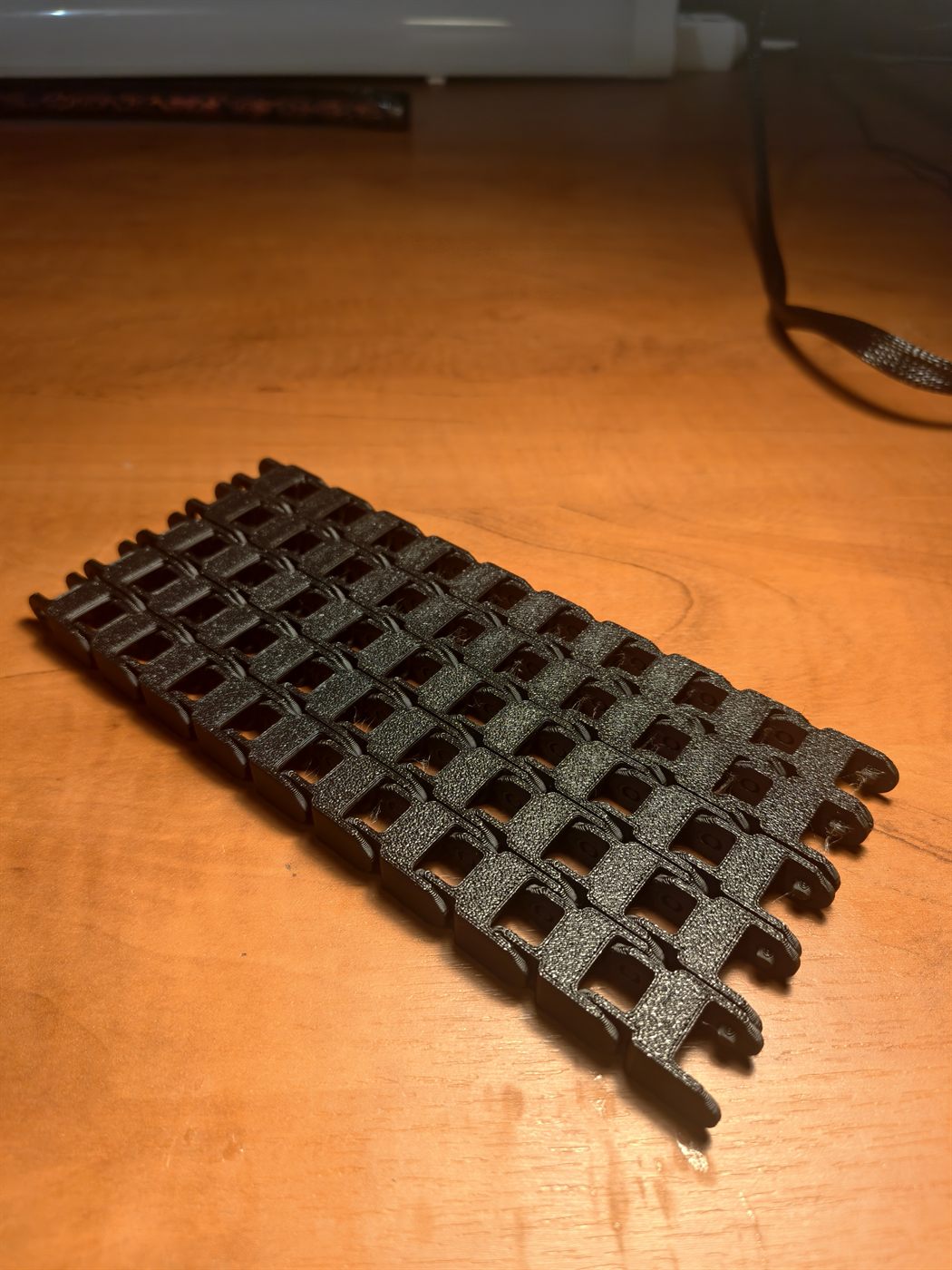 Czarny elastyczny tor modułowy z połączonych ogniw, druk 3D z PETG (print-in-place)